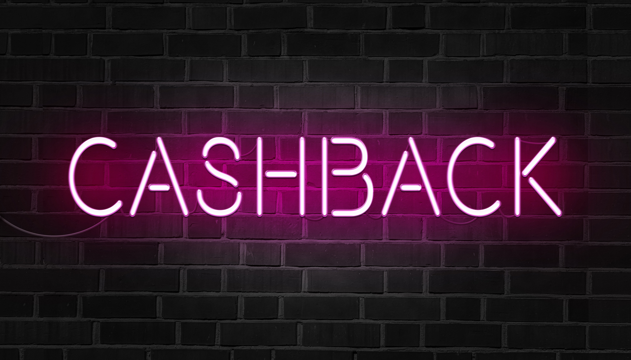 Pink neon sign of the word cashback on dark brick wall.